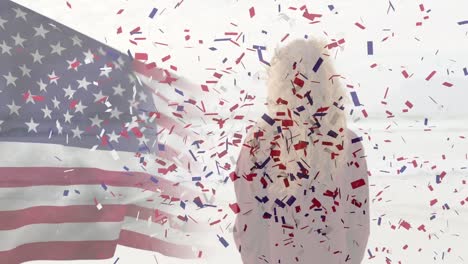 animation of american flag and confetti over caucasian woman at beach