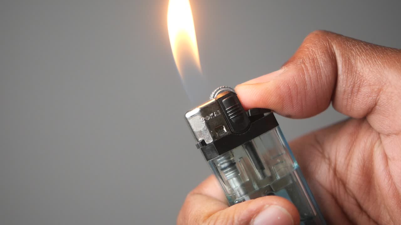 mano con un encendedor con una llama encendida