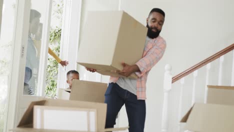 happy african american couple with son and daughter bringing boxes into house, slow motion