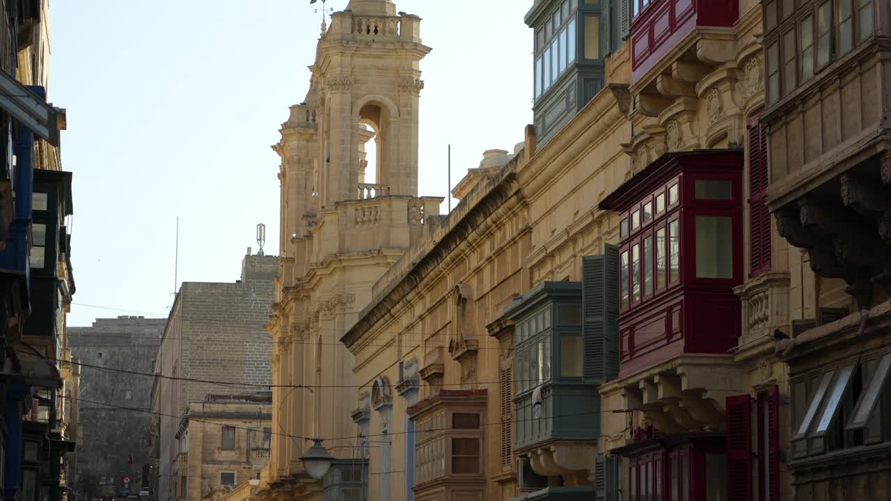 Limestone buildings with colourful windows and church spires in Valetta, Malta