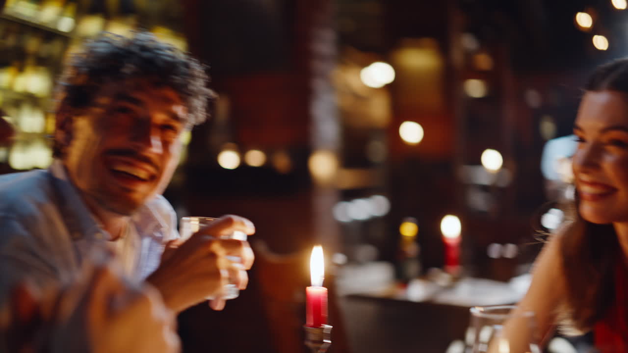 Allegro gruppo di amici che ridono seduti al bar durante un fine settimana sera, primo piano. Due coppie