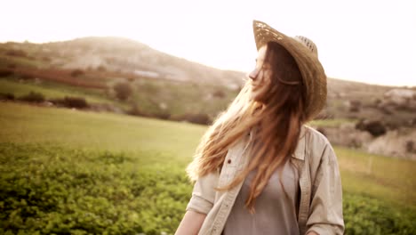 young woman farmer walking in green field in the country