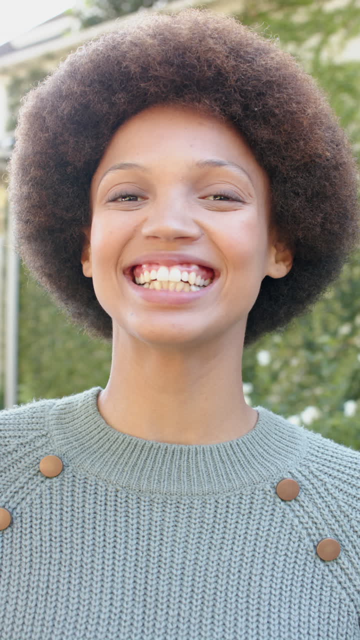Vertical video of portrait of happy african american woman in garden