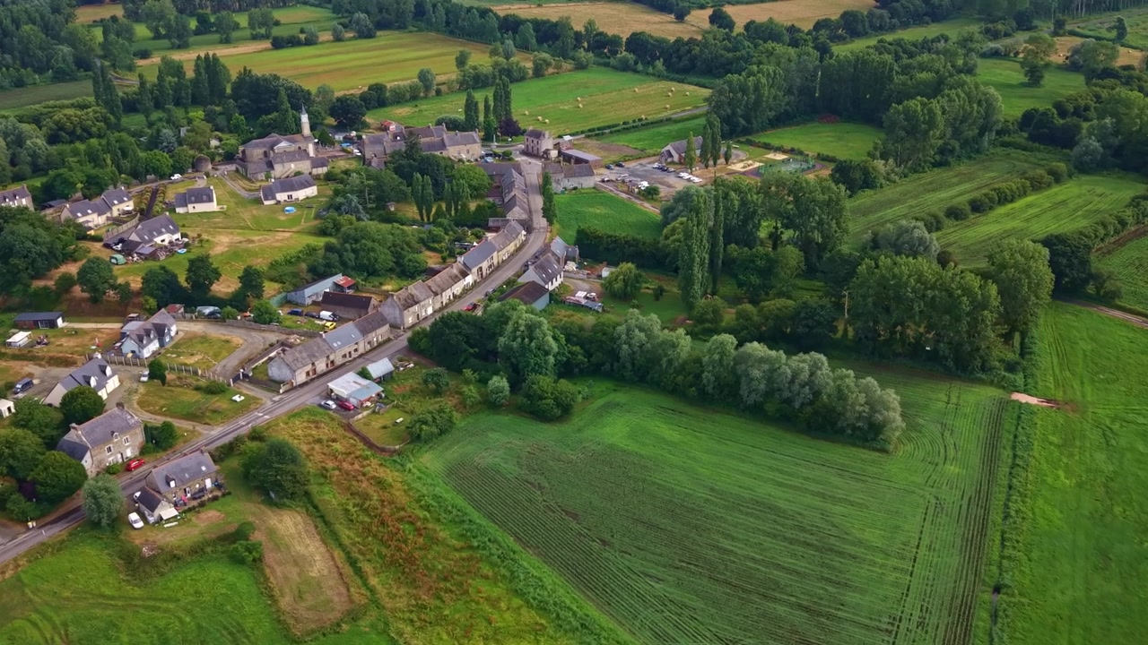 Lähestyvä drone-lento Lillemerin pieneen kuntaan ja sen kauniiseen maisemaan, jossa kirkontorni on viljelysmaiden ympäröimänä, Ille-et-Vilaine, Bretagne, Ranska.