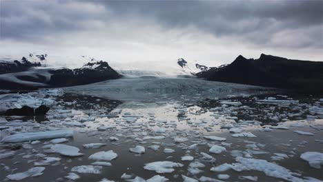 Drone-flying-towards-a-large-glacier-over-a-lake-with-chunks-of-ice-in-Iceland-4k