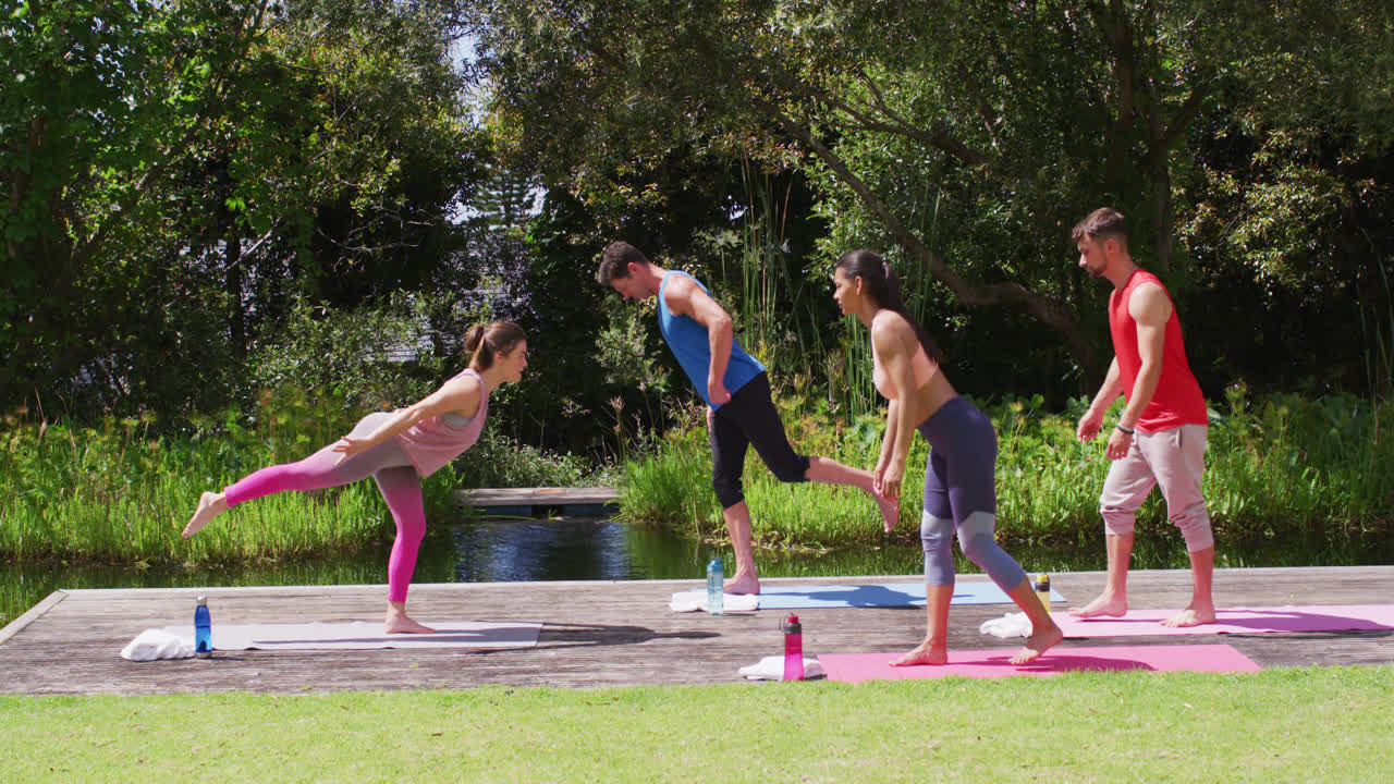 instructora de yoga caucásica y grupo diverso practicando la postura de yoga en el parque soleado
