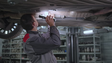 el mecánico inspecciona el sistema de escape del automóvil en el servicio de automóviles