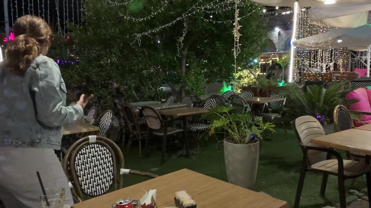 Woman Leaving a Beautifully Lit Outdoor Cafe at Night