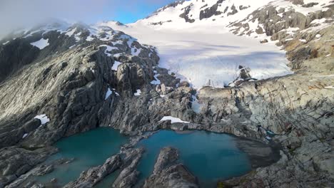 young woman enjoying stunning view of glacier hanging from mountain peak after challenging hike in new zealand - aerial drone