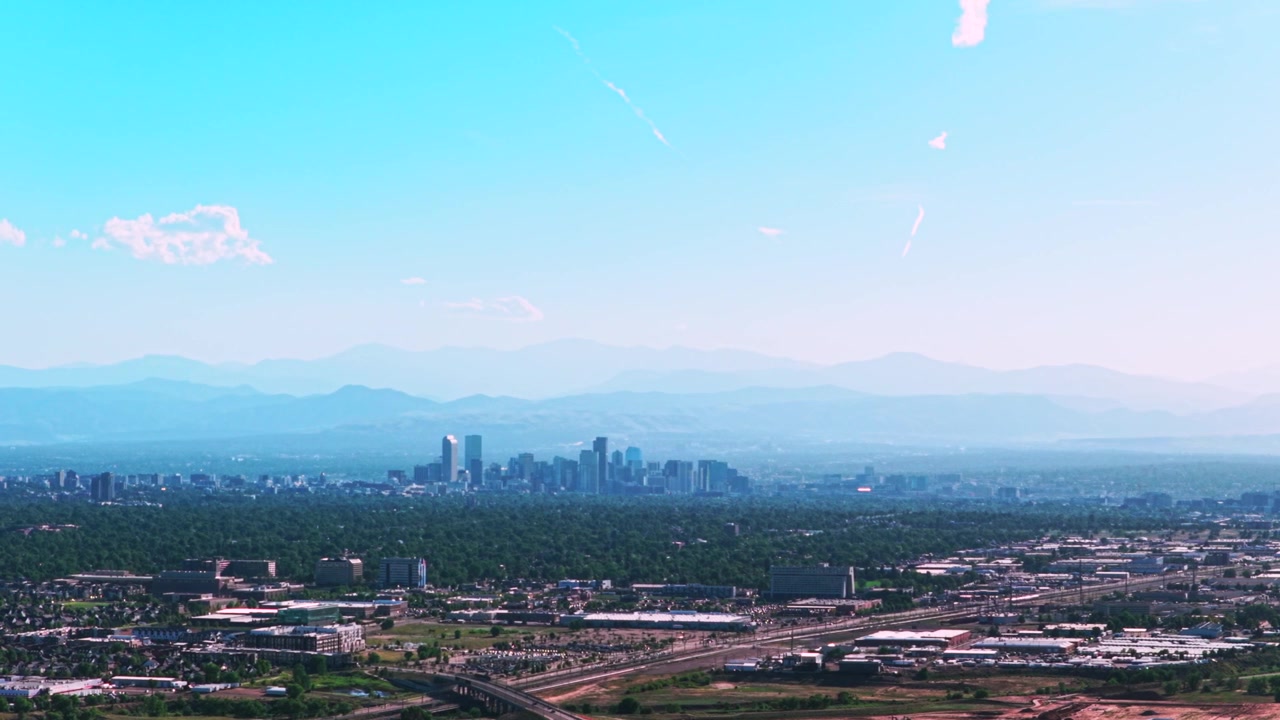 Foschia fumosa sul paesaggio urbano del centro di Denver, Front Range, con grattacieli ed edifici. Vista aerea con drone del Colorado, auto e traffico, colline e strati delle Montagne Rocciose. Estate, primavera, cieli blu, mattina, panoramica a sinistra