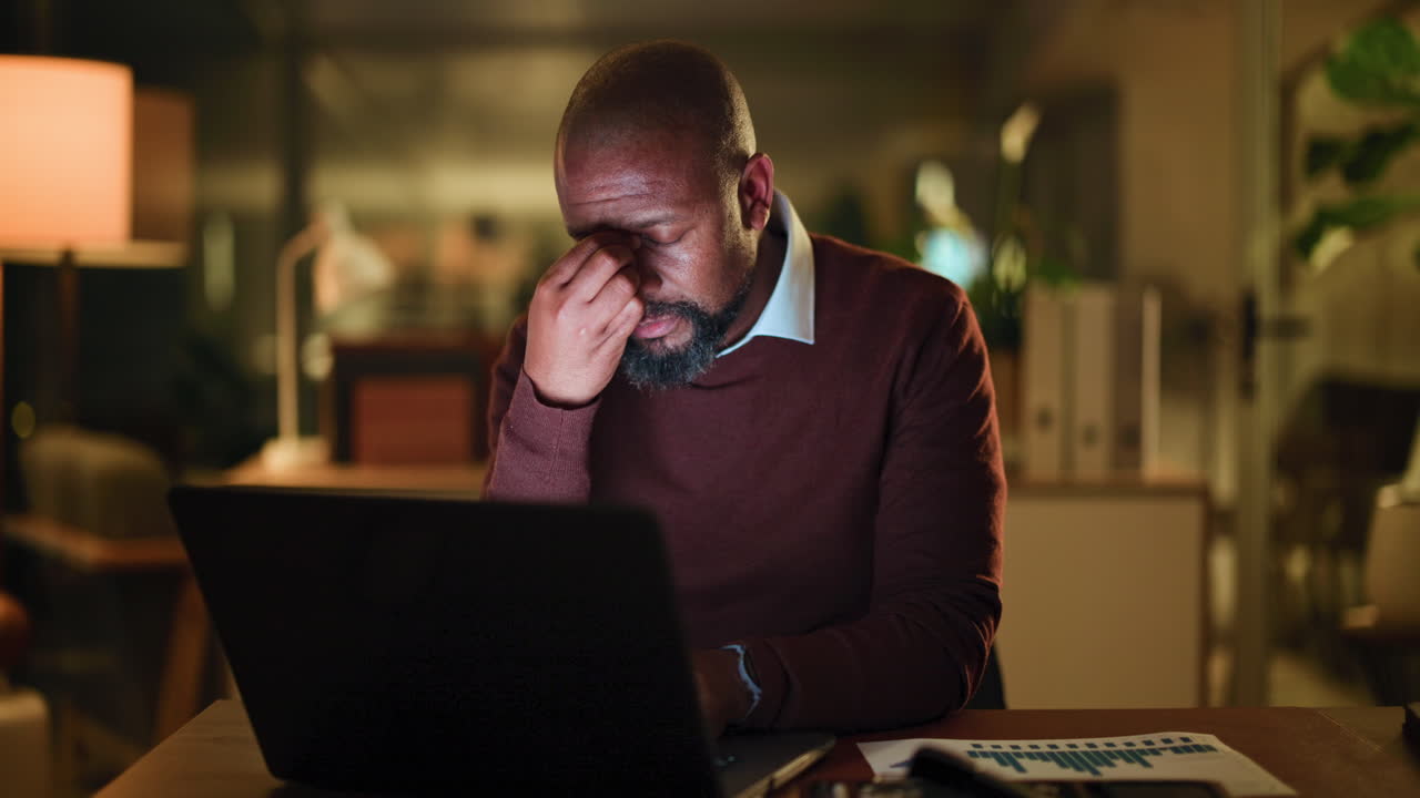 Müder Mann arbeitet bis spät in die Nacht am Laptop