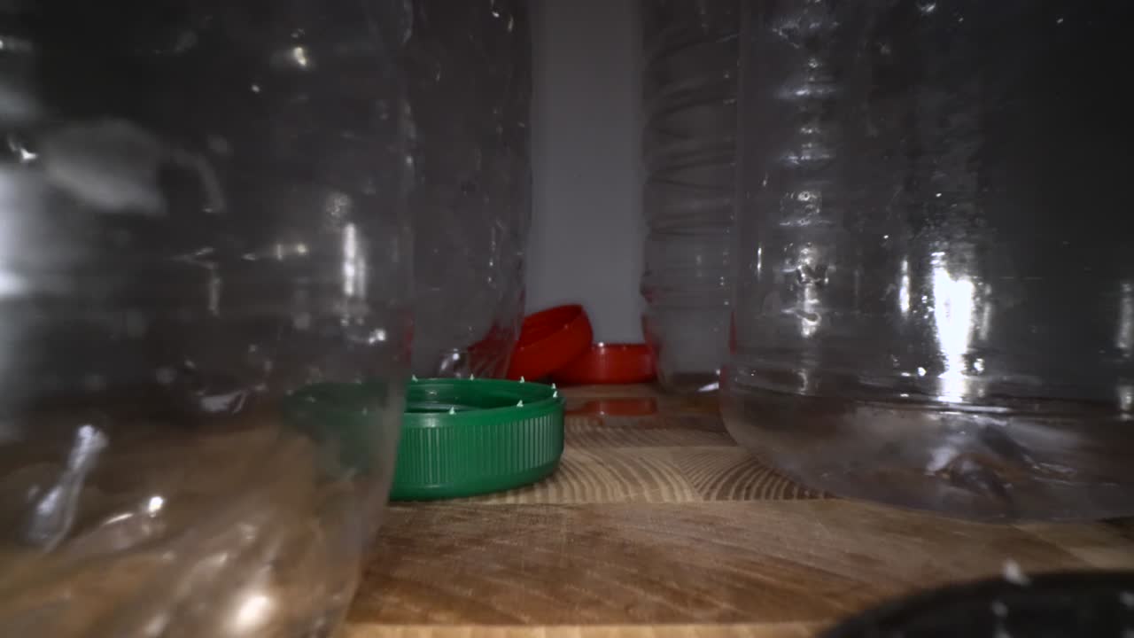 cámara deslizante a través de botellas de plástico vacías con tapas de botella sobre fondo de madera. residuos de plástico transparentes y reutilizables. reciclaje de plástico, cuestiones ambientales