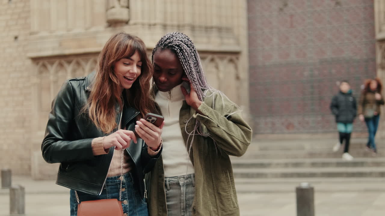Due giovani amiche che usano lo smartphone in città