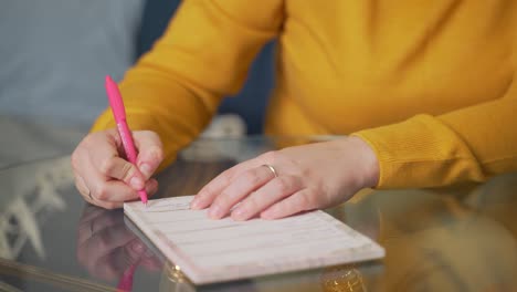 woman is writing something on sheets of paper at glass table with pen. she reads something and corrects it with pen. studying something, preparing for speech, checking contract, training, lecture