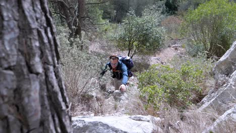 disparo en cámara lenta de un hombre subiendo y usando sus manos para subir a la ladera