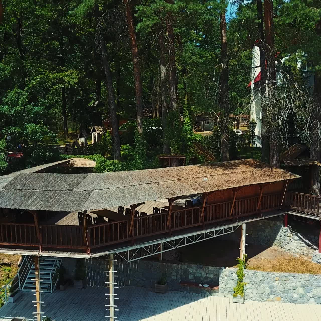 Beautiful two-storied pier at the river bank. White three-storied cottage hiding among the pine woods. Sunny summer day backdrop
