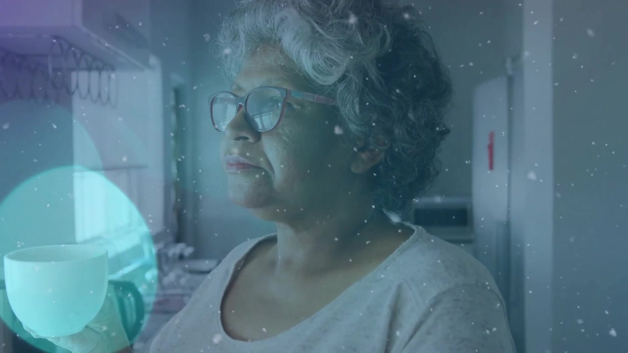 Senior woman in kitchen lifting mug up sipping and gazing out with floating wellness particles