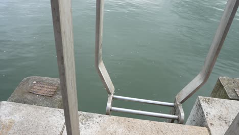 steel marina ladder leading to idyllic ocean water reflections waterfront slow pull back