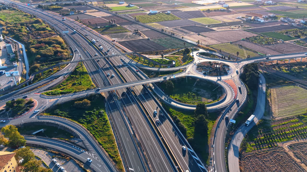 Wide aerial panorama of Port Saplaya and highway. Extensive view of coastal marina buildings, highway traffic, and tilled agricultural fields in Spain