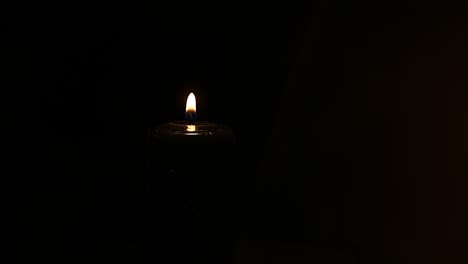 burning black candle close up swirls on a black background with gold bokeh. selective focus.