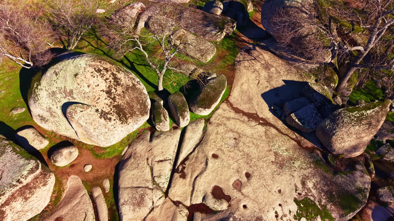 Las formaciones rocosas en un paisaje natural muestran texturas y patrones bajo la luz brillante del sol, con sombras proyectadas alrededor del área.