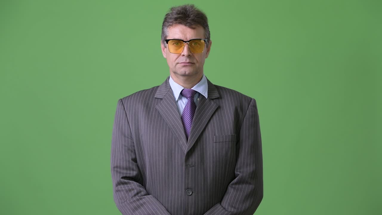 hombre de negocios maduro y guapo contra un fondo verde