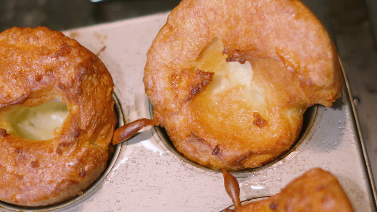 Vista dall'alto di Yorkshire Pudding dopo la cottura su una teglia. Perfetti per spot pubblicitari di cibo di alta gamma, promozioni per l'arrosto domenicale britannico e intestazioni di ricette appetitose