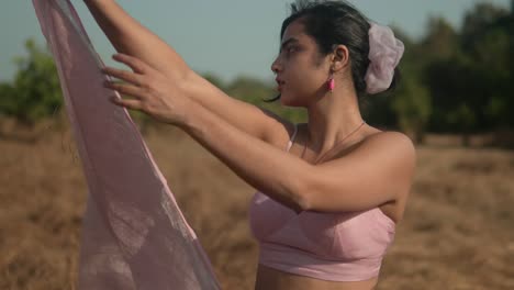 woman in pink wrapping fabric around her, outdoors, sunny day, tranquil mood, natural setting