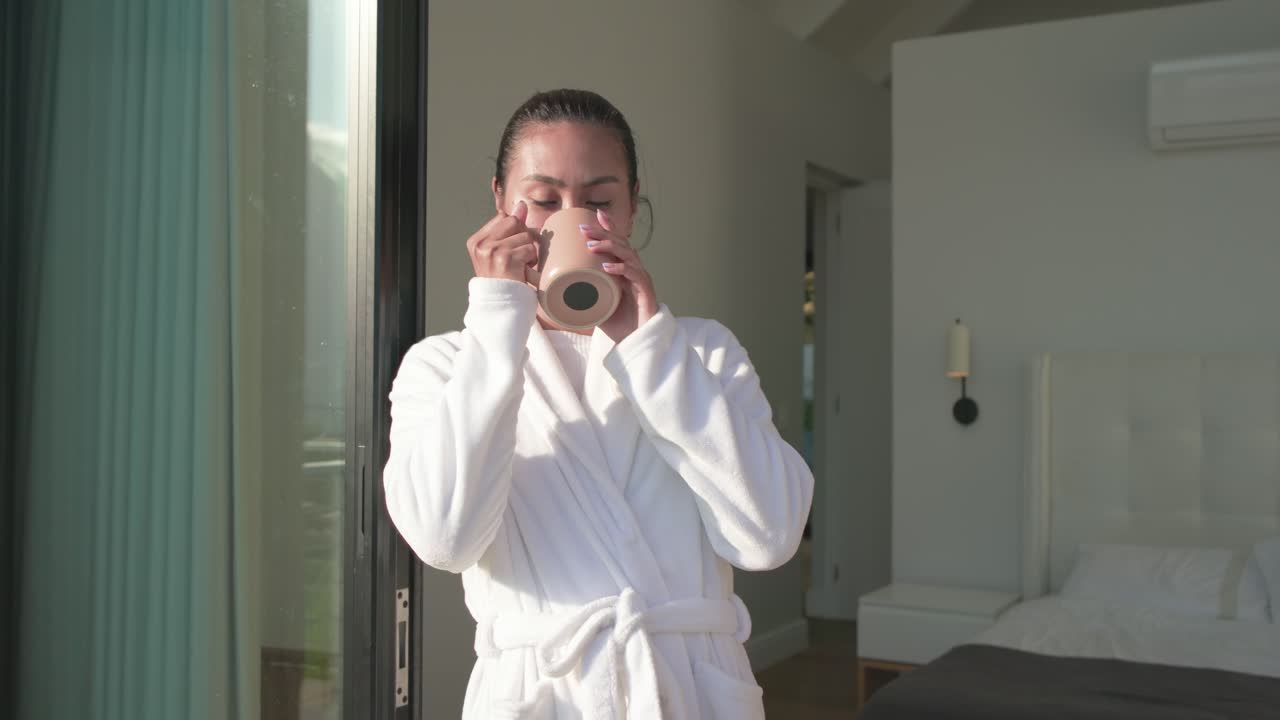 Morning light guiding woman wearing bathrobe stepping onto balcony, sipping mug, savoring sunlight