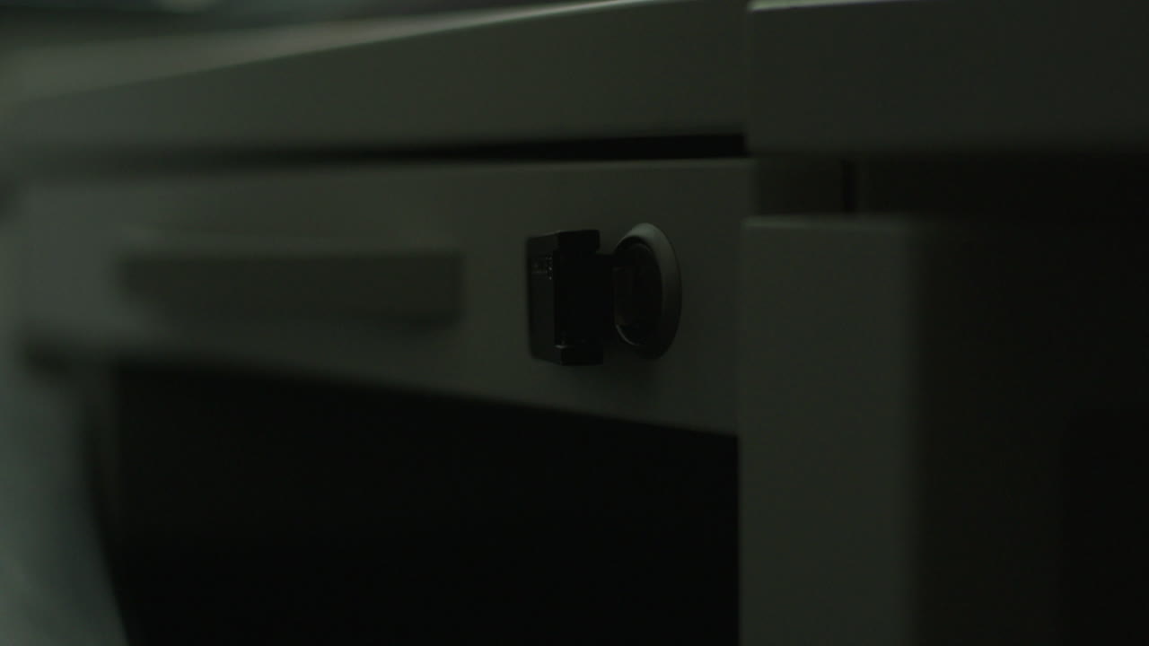 Close-up of a drawer lock on a white desk