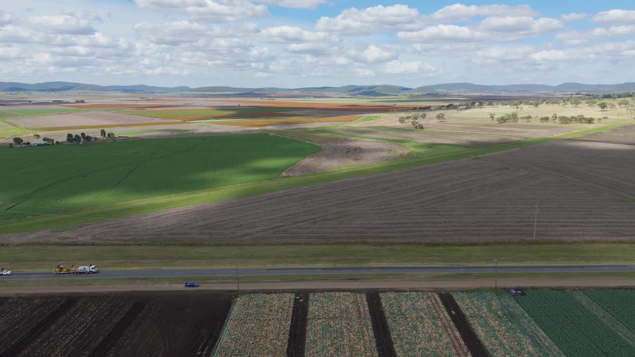 Vehicles drive past fields and farmhouses