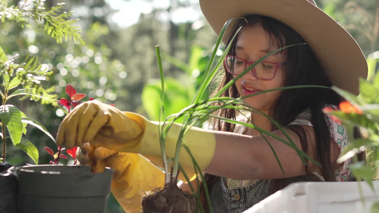 niña con guantes amarillos plantando una planta de cebolla en una olla