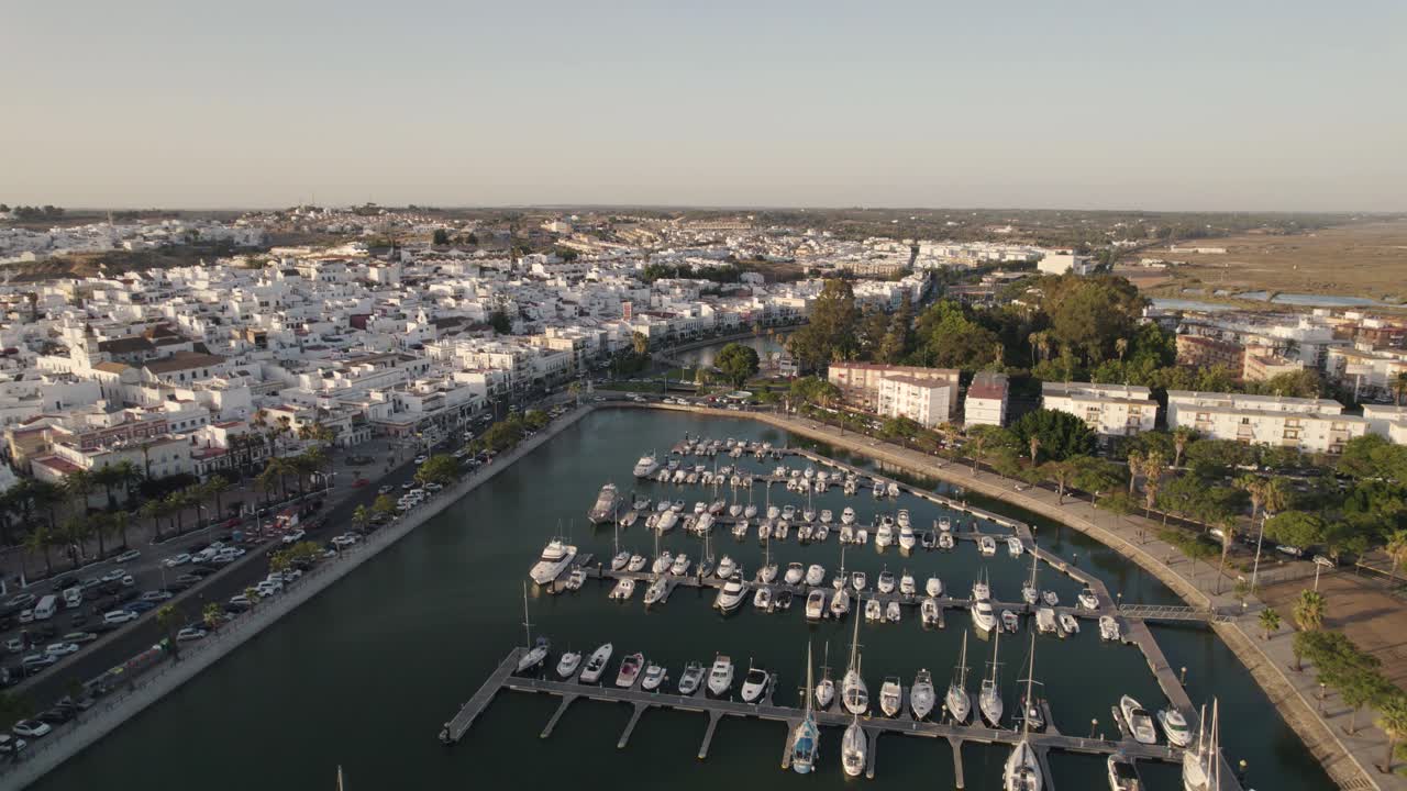 Flygbild som drar sig tillbaka och avslöjar Ayamonte marina, en spansk kustby med vita hus i landskapet.