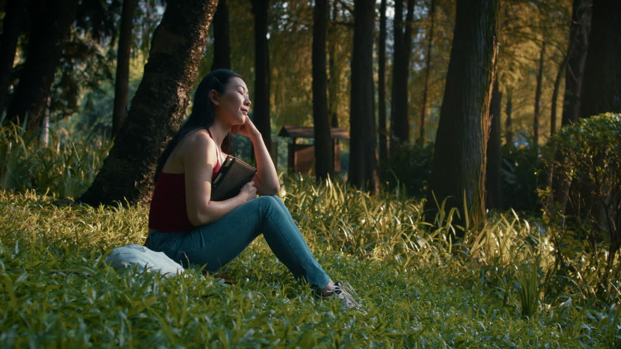 Donna che legge in un parco boschivo