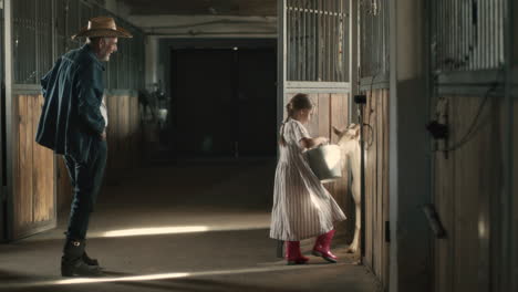 grandparent and grandchild feeding horses in a stable