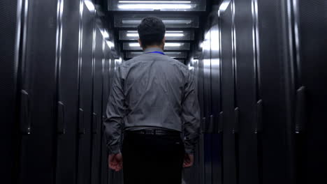 data center technician: a lone technician walks down a long corridor of brightly lit server racks in a modern data center server room.