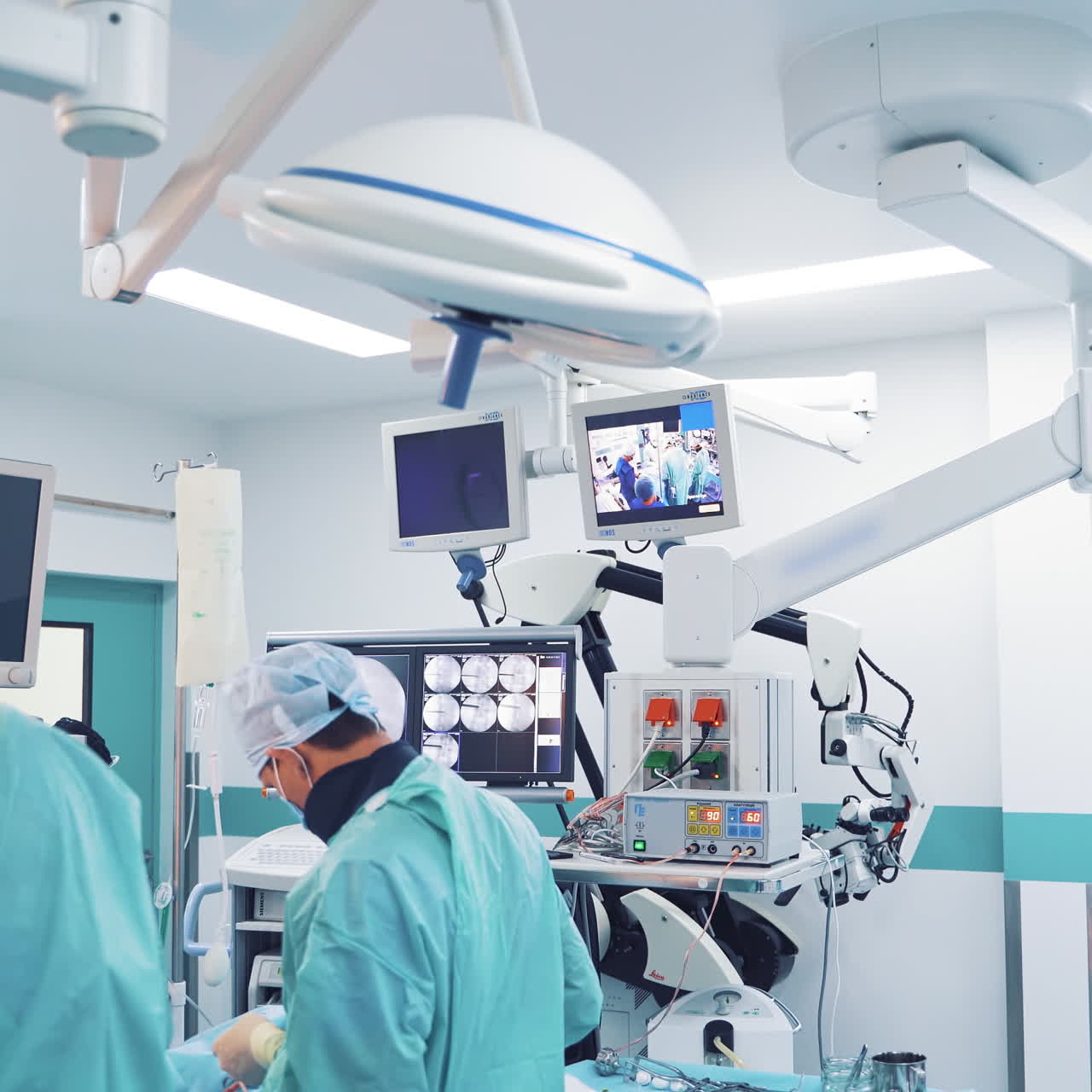 Modern medical equipment in the light operating room. Surgeons are performing an operation to a patient on the background of contemporary furnishing in a surgery cabinet.