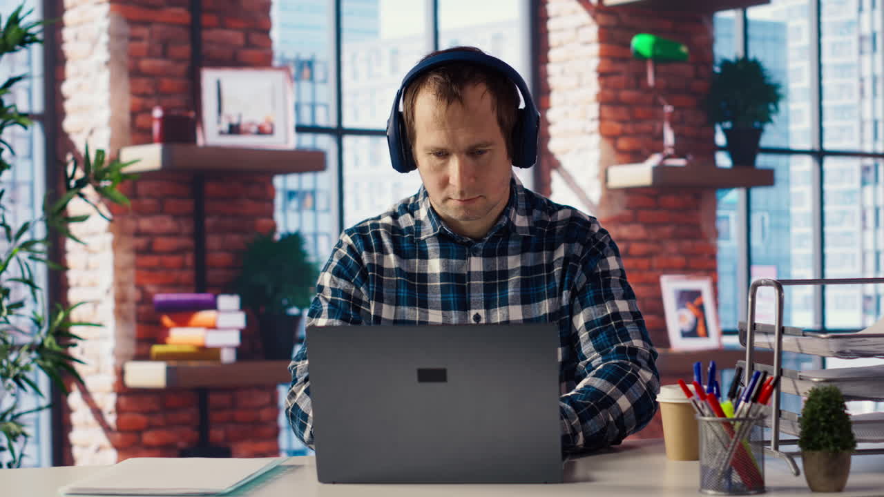 trabajador escribiendo en papel, tomando notas, escuchando música en la computadora portátil