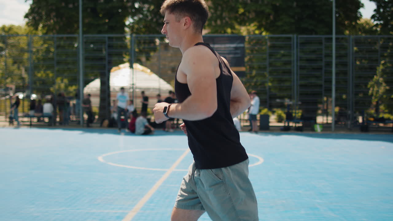 Athletic caucasian sports man in sportswear jogging running on urban basketball court outdoors