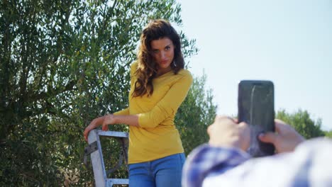 hombre tomando una foto de una mujer con teléfono móvil en una granja de olivos 4k