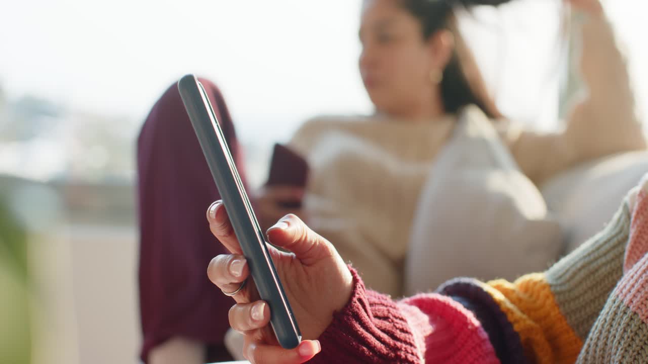 User rotating smartphone, tilting phone toward camera in living room while friend tapping red phone