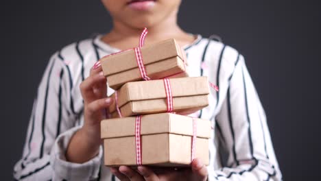 child holding stacked gift boxes