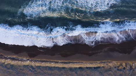 aerial drone view of waves crashing in to the shoreline of south coast beach - static shot