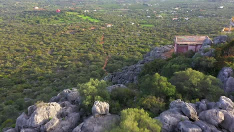 Drone-Flies-over-rocky-Cliff-during-the-day-to-reveal-epic-green-scenic-landscape,-Aerial