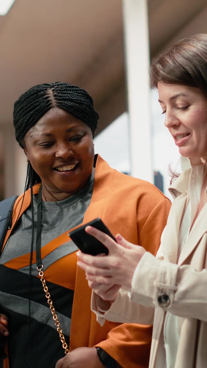 Vertical video Close up of female tourists looking at smartphone in bus terminal