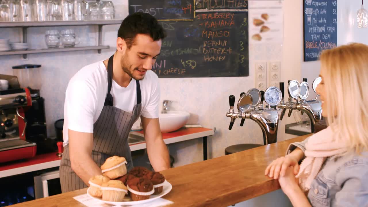 Tjener serverer kaffe til kvindelig kunde ved disken