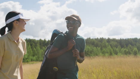 una mujer caucásica y un hombre afroamericano en el campo de golf.