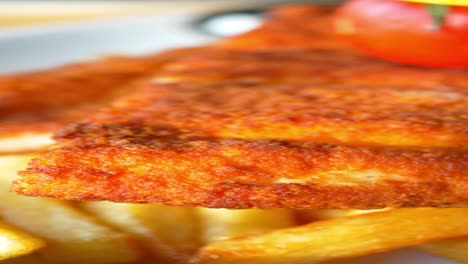 close-up of crispy breaded chicken with french fries and tomato