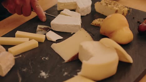 cutting mixed cheese selection with soft warm lighting close up