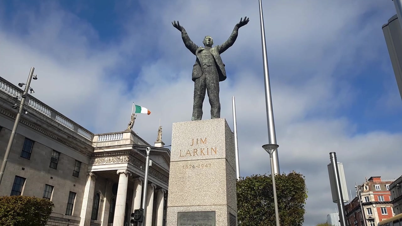 Video dell'Ufficio Postale Generale (GPO) di Dublino in O'Connell Street a Dublino, con la bandiera irlandese a sinistra e lo Spire a destra, al centro un monumento a James Larkin.